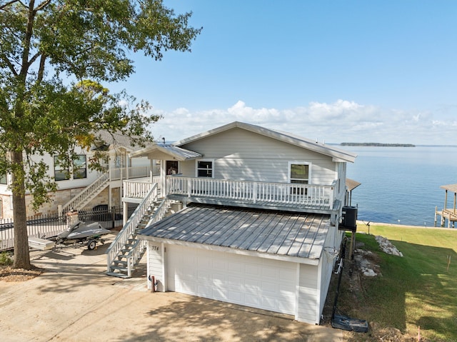 view of front of property with a front lawn, a garage, and a water view