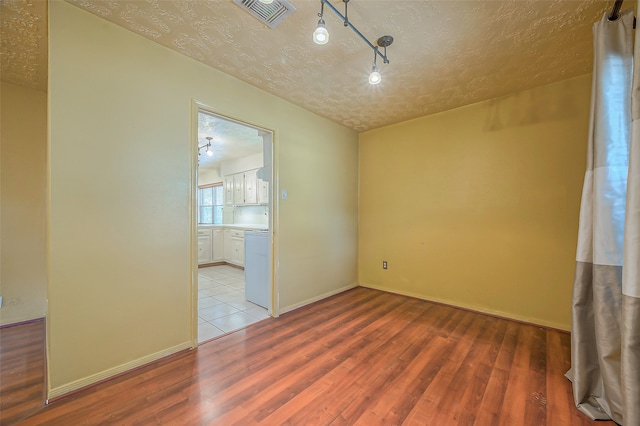 unfurnished room with a textured ceiling and light wood-type flooring