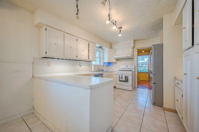 kitchen with stainless steel appliances, white cabinets, kitchen peninsula, a textured ceiling, and light tile patterned floors