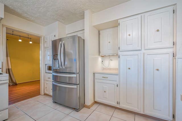 kitchen featuring white cabinets, light wood-type flooring, white appliances, and a textured ceiling