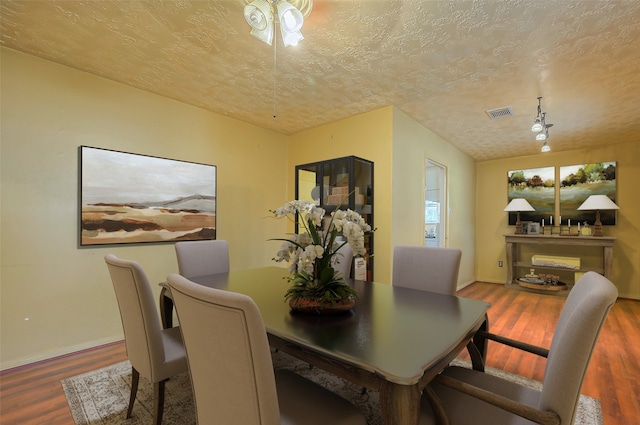 dining space with hardwood / wood-style floors and a textured ceiling