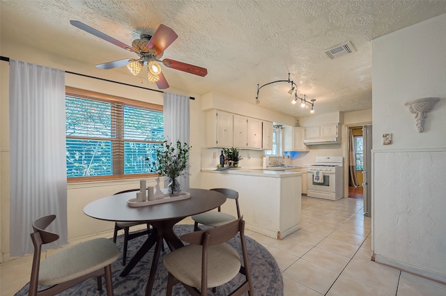 kitchen with a textured ceiling, kitchen peninsula, white cabinets, and white stove