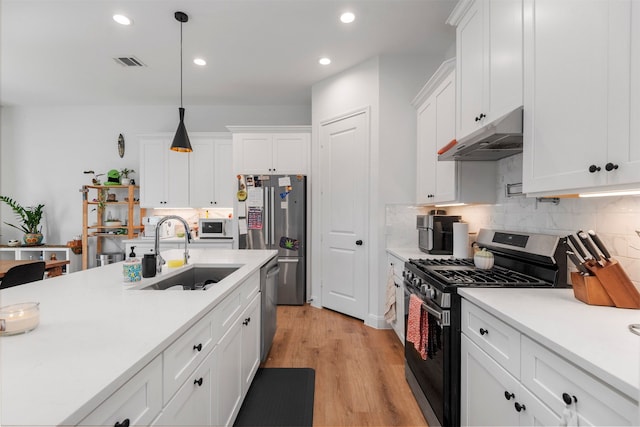 kitchen with white cabinetry, stainless steel appliances, sink, and hanging light fixtures