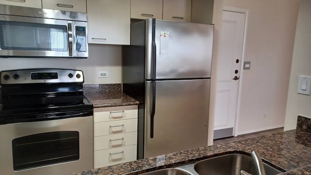 kitchen with stainless steel appliances and dark stone countertops