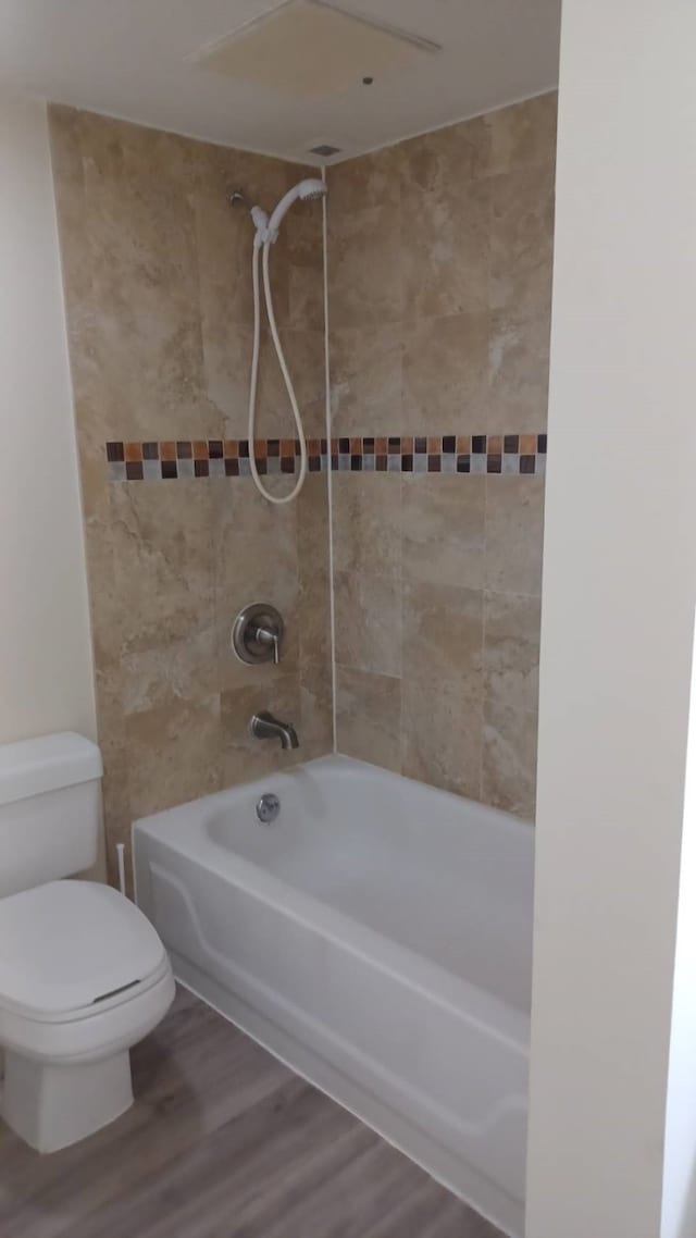 bathroom featuring toilet, tiled shower / bath combo, and wood-type flooring