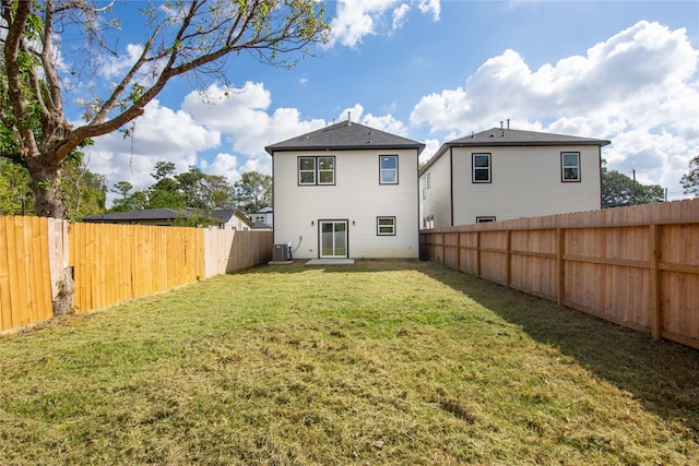 back of property with central air condition unit and a lawn