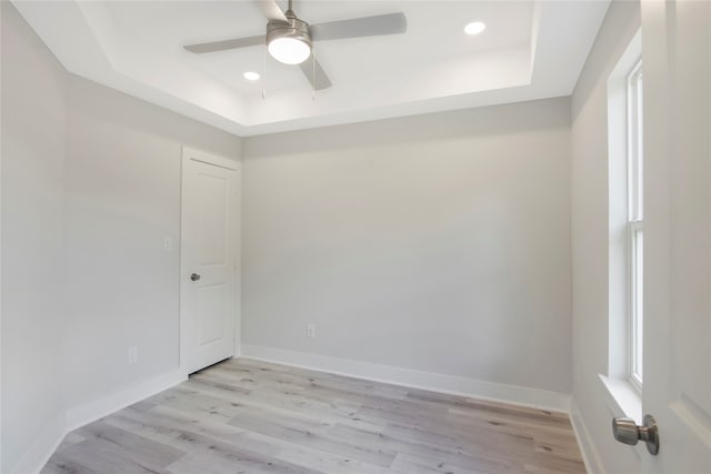 spare room with ceiling fan, light hardwood / wood-style floors, and a raised ceiling