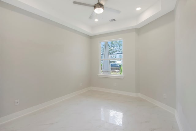 spare room featuring ceiling fan and a raised ceiling