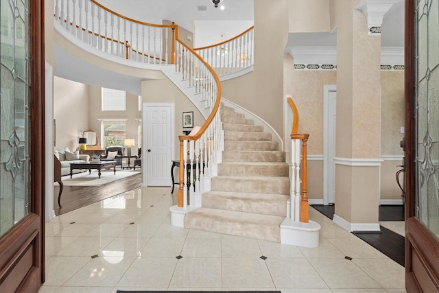 tiled foyer with a high ceiling and crown molding