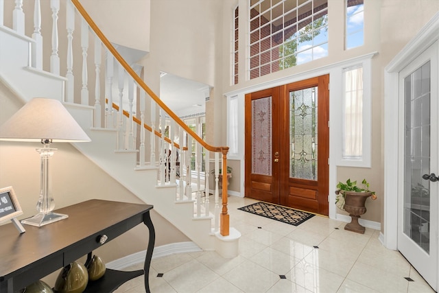 entryway featuring french doors, light tile patterned floors, and a high ceiling