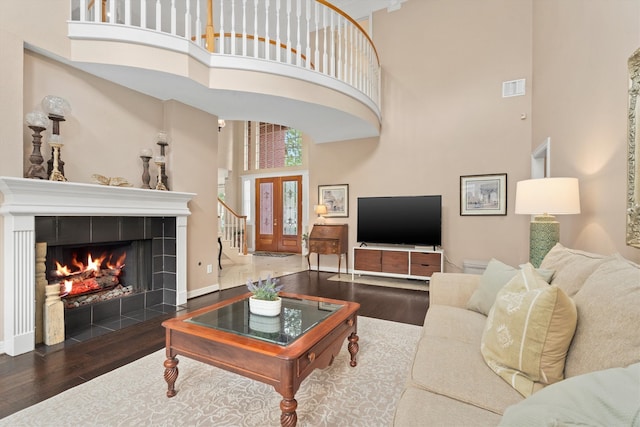 living room featuring a fireplace, dark hardwood / wood-style floors, and a towering ceiling