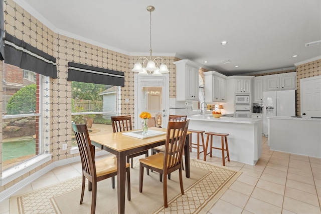 tiled dining space with crown molding, sink, and a notable chandelier