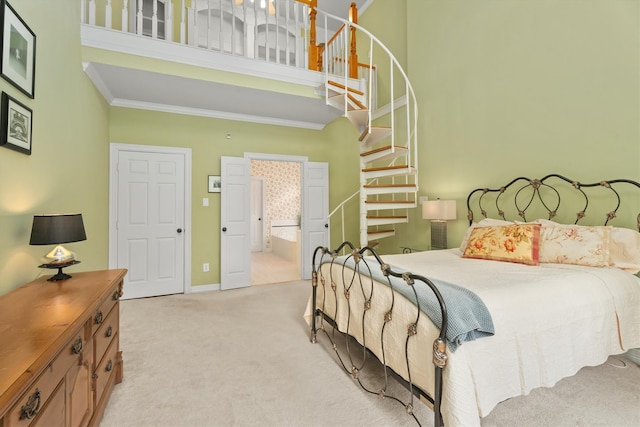 carpeted bedroom featuring a high ceiling, ornamental molding, and ensuite bath