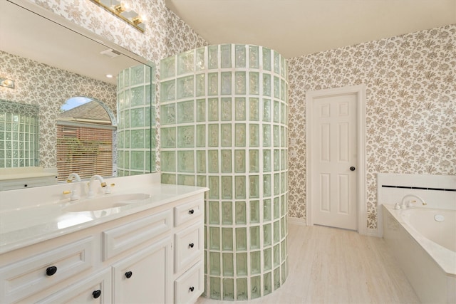 bathroom with hardwood / wood-style flooring, vanity, and a tub to relax in