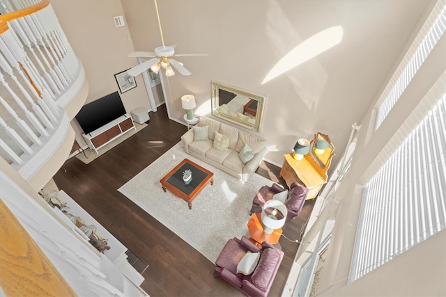 living room featuring dark hardwood / wood-style flooring, ceiling fan, and a high ceiling