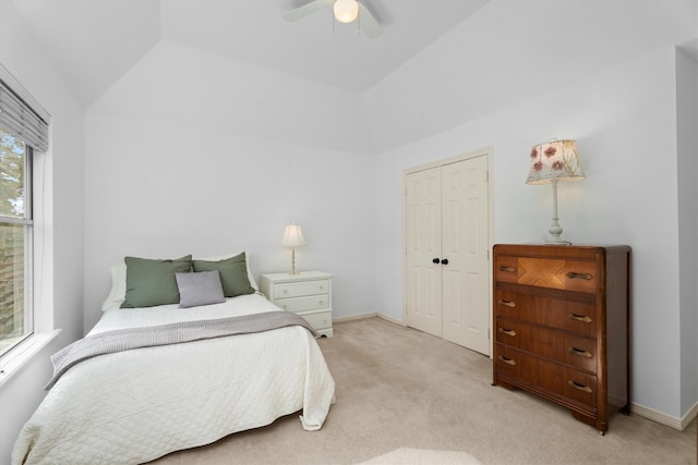 bedroom with lofted ceiling, light carpet, ceiling fan, and a closet