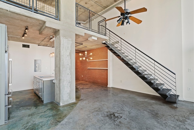 unfurnished living room featuring ceiling fan and a towering ceiling