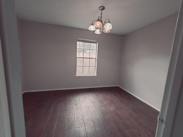 empty room with dark hardwood / wood-style floors and an inviting chandelier