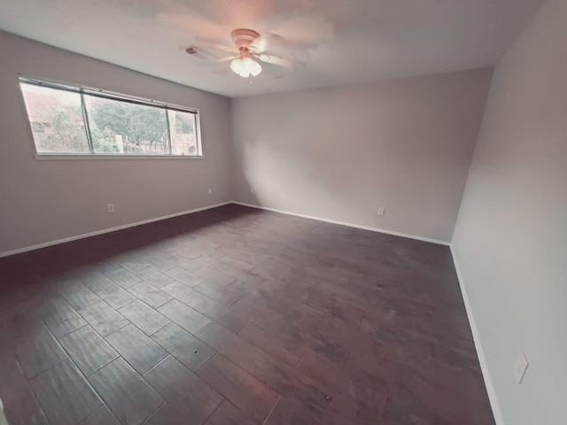 spare room with dark wood-type flooring and ceiling fan