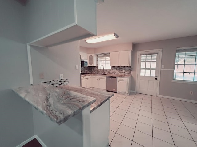 kitchen with tasteful backsplash, appliances with stainless steel finishes, sink, kitchen peninsula, and white cabinets