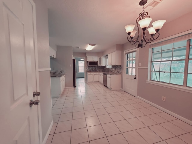 kitchen featuring appliances with stainless steel finishes, white cabinetry, hanging light fixtures, and a wealth of natural light