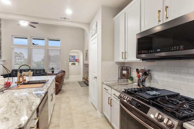 3522 Lake Lugano Cir, Katy, TX 77493 - kitchen featuring appliances with stainless steel finishes, a sink, ceiling fan, light stone countertops, and decorative backsplash