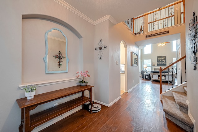 foyer entrance featuring crown molding, hardwood / wood-style flooring, and a towering ceiling