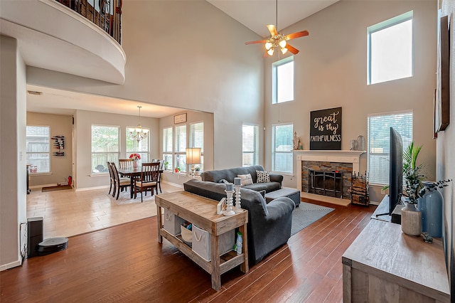 living room featuring a high ceiling, a stone fireplace, and hardwood / wood-style flooring