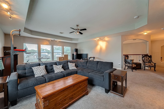 living room with ceiling fan, carpet, and a raised ceiling