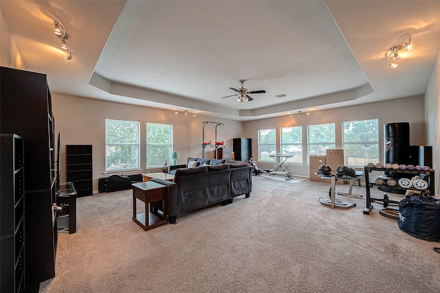 carpeted living room with ceiling fan, a raised ceiling, track lighting, and a wealth of natural light