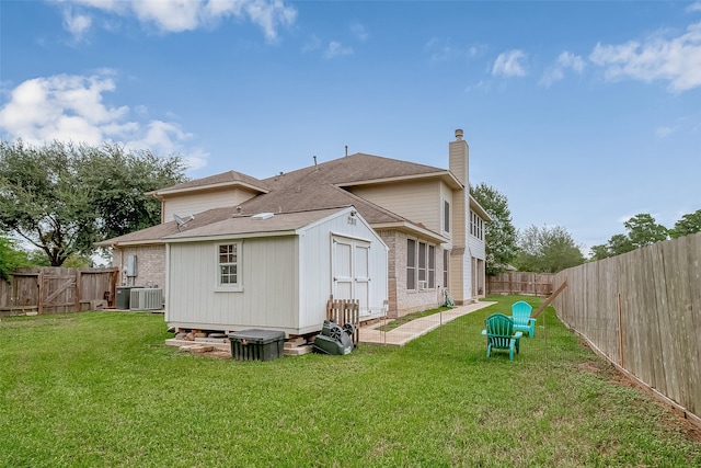 rear view of house with central air condition unit and a yard