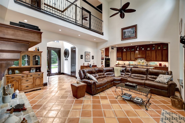 tiled living room with ceiling fan and a high ceiling