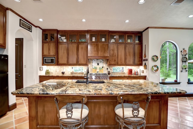 kitchen with a spacious island, light stone counters, and stainless steel microwave