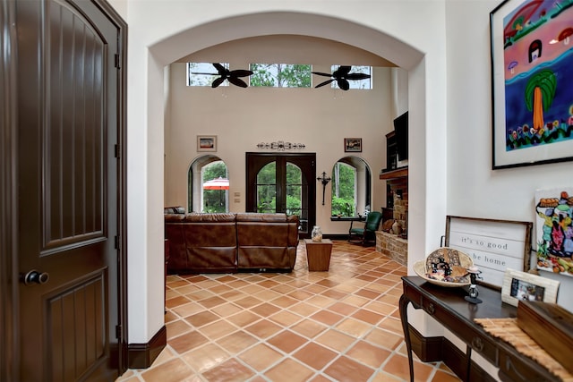 tiled foyer entrance featuring ceiling fan, a towering ceiling, and a fireplace