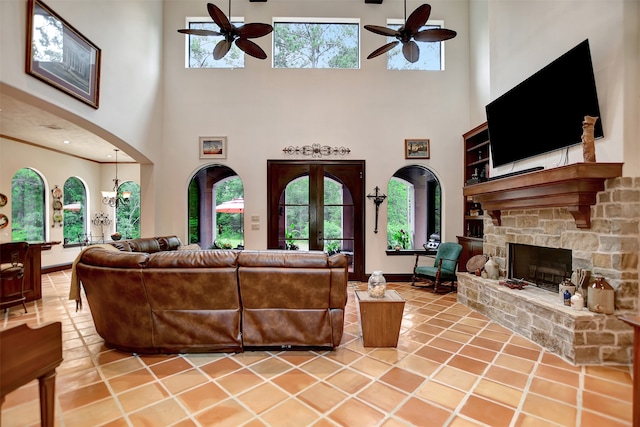 tiled living room featuring ceiling fan with notable chandelier, a high ceiling, and a wealth of natural light