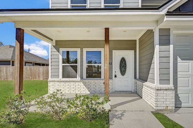 view of exterior entry with a yard, covered porch, and a garage