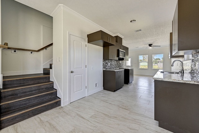 kitchen featuring crown molding, sink, light stone countertops, a textured ceiling, and ceiling fan