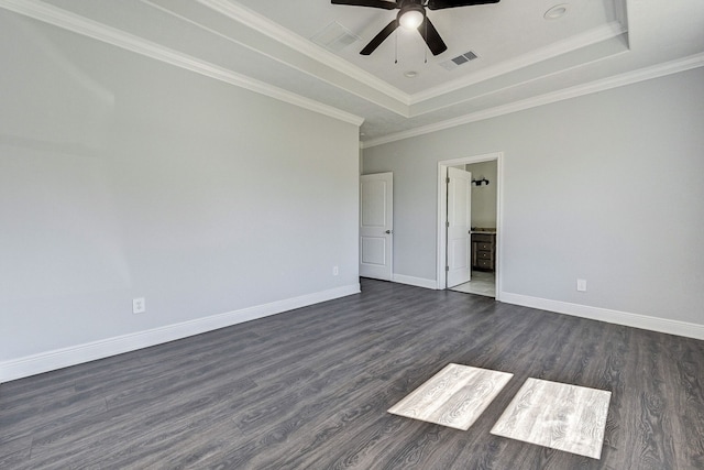 empty room featuring dark wood-type flooring, crown molding, and a tray ceiling