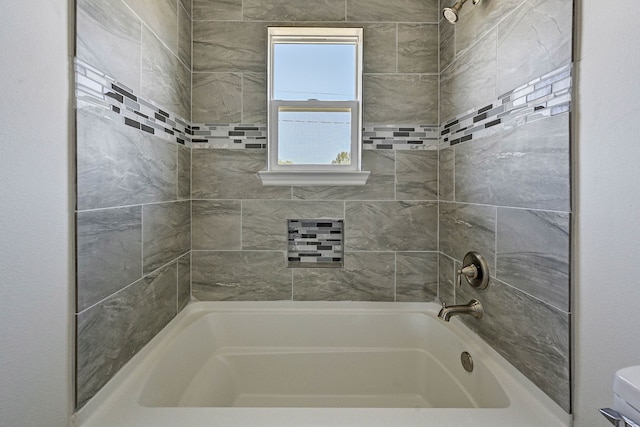 bathroom with toilet and tiled shower / bath combo