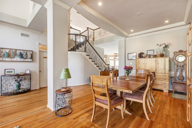 dining room with ornamental molding, light hardwood / wood-style floors, and a textured ceiling