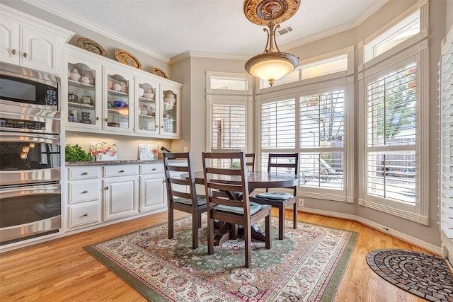 dining area featuring ornamental molding, light hardwood / wood-style floors, and plenty of natural light