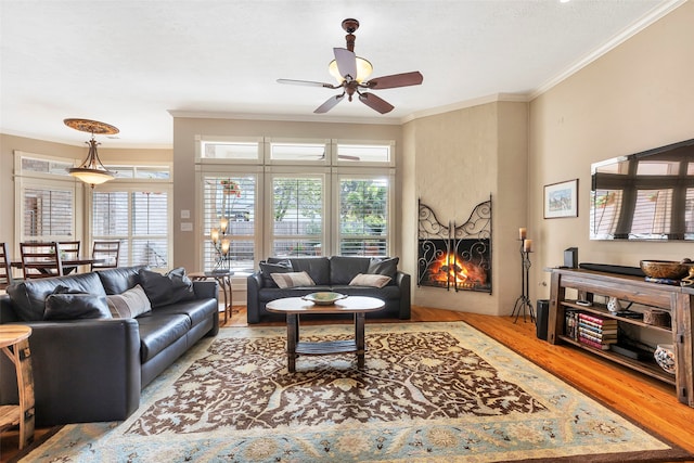 living room featuring ceiling fan, crown molding, and light wood-type flooring