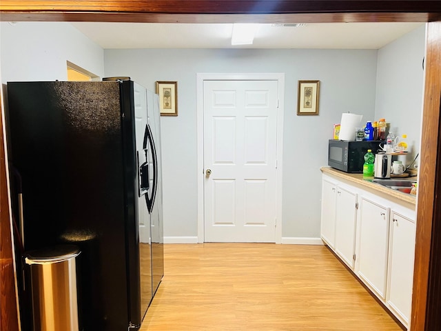 kitchen with black appliances, white cabinets, and light wood-type flooring