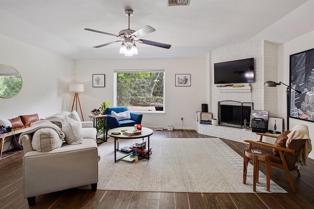 living room with a fireplace, dark hardwood / wood-style floors, and ceiling fan