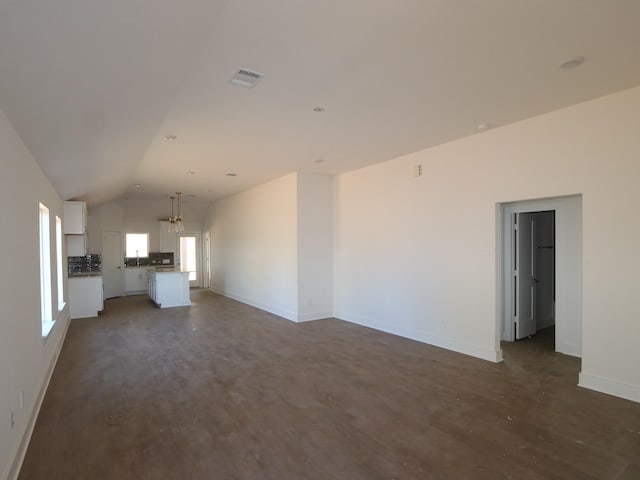 unfurnished living room with lofted ceiling, dark wood-type flooring, and a chandelier