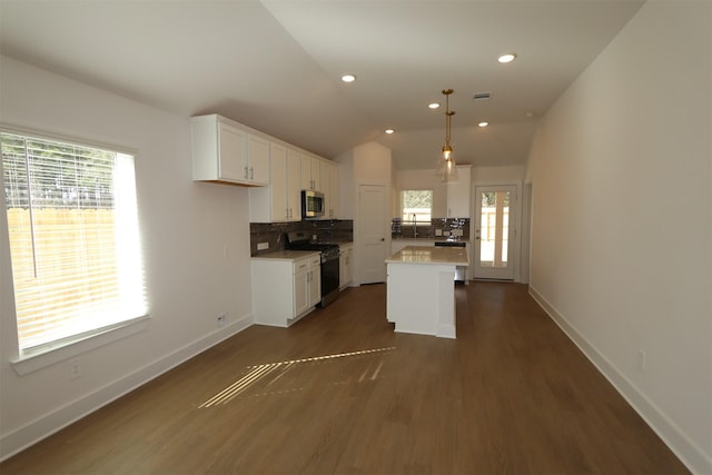 kitchen with white cabinets, stainless steel microwave, vaulted ceiling, backsplash, and gas stove