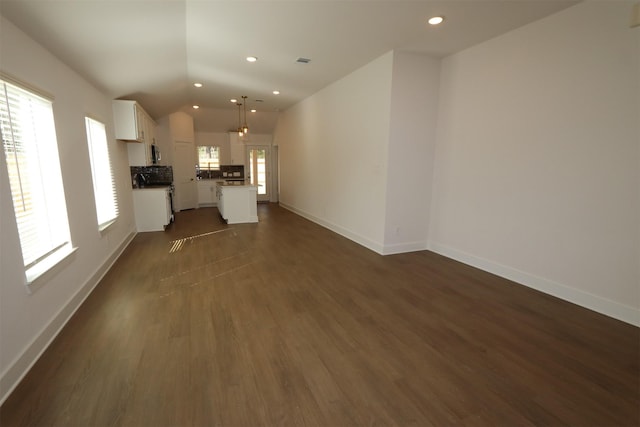 unfurnished living room with visible vents, baseboards, lofted ceiling, dark wood-style flooring, and recessed lighting