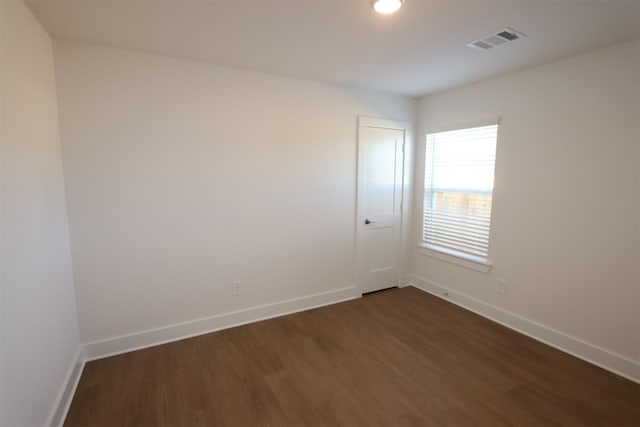 unfurnished room with dark wood-style floors, visible vents, and baseboards