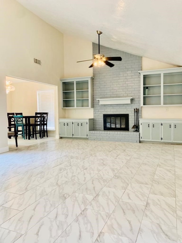 living room featuring ceiling fan, high vaulted ceiling, built in shelves, and a brick fireplace