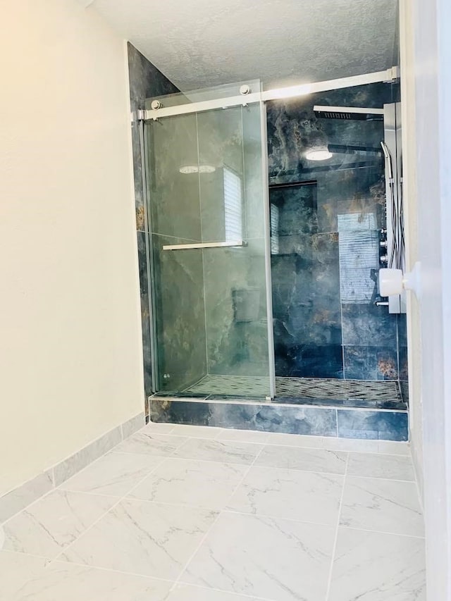 bathroom with a shower with shower door and a textured ceiling